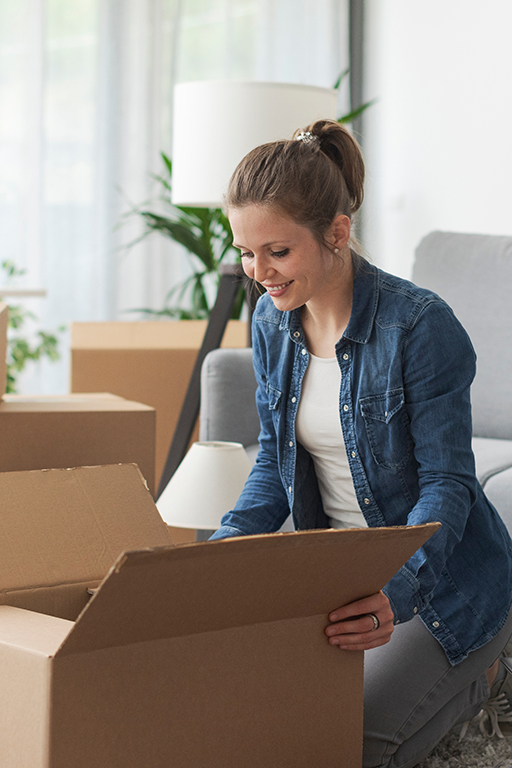 Junge Frau räumt Umzugskartons aus, als Symbolbild für Ratgeber Untervermietung. Foto: StockPhotoPro, Adobe Stock
