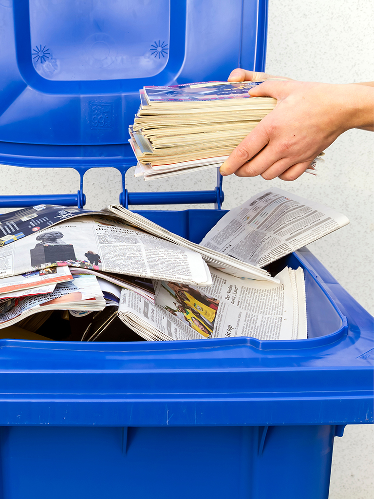Das Befüllen einer Altpapiertonnen, mit alten Zeitungen, als Symbolbild für den Ratgeber zur Papiertonne. Foto: nemo1963, AdobeStock