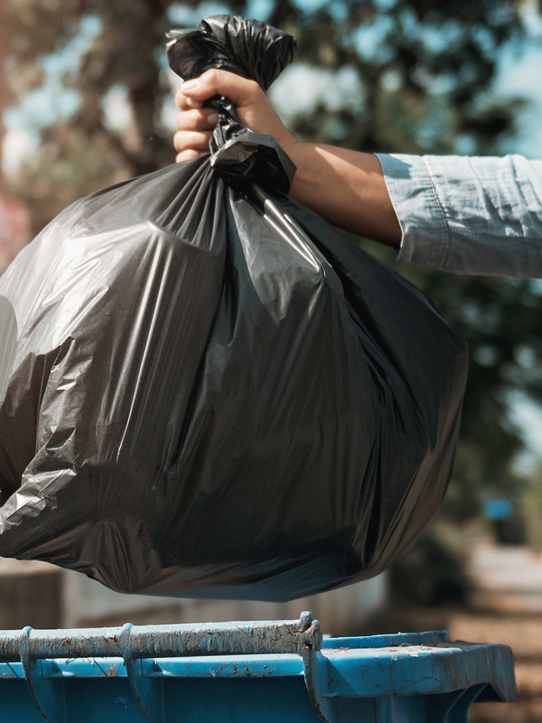 Die Hand einer Frau entsorgt Restmüll, als Symbolbild für den Ratgeber zur Restmüllentsorgung. Foto: lovelyday12, AdobeStock