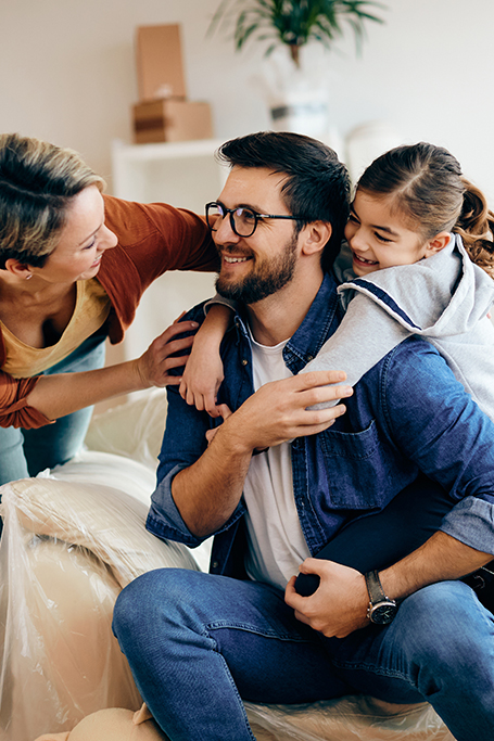 Familie sitzt glücklich in ihrem neuen Zuhause in Freital und hat Spaß. Foto: Drazen, AdobeStock
